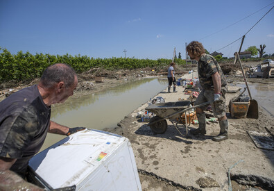 Volontari ripuliscono dal fango una casa alluvionata (ANSA)