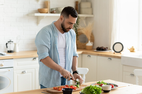 Un uomo in cucina prepara una insalata foto iStock.