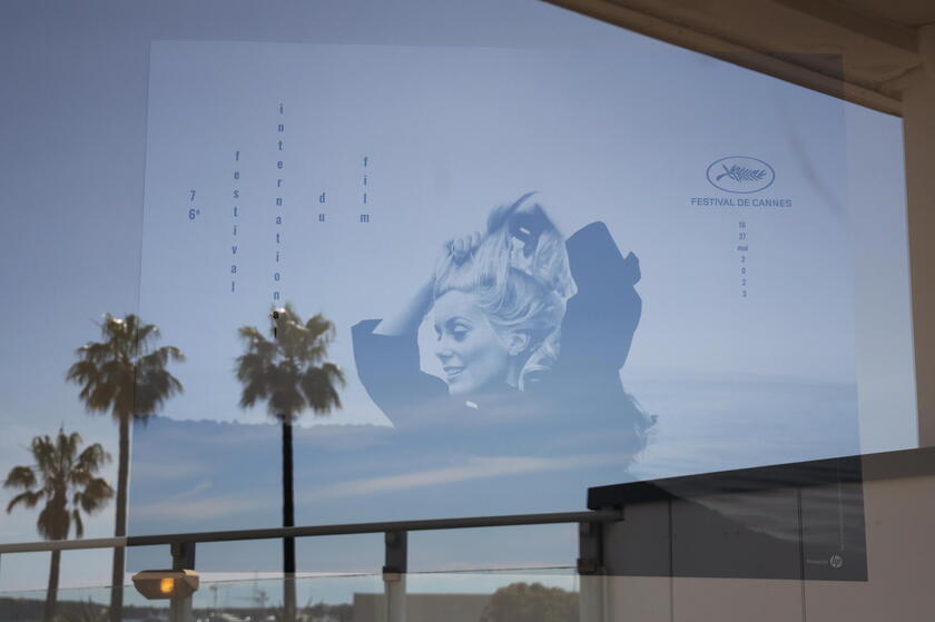 Il poster del festival di quest 'anno con una giovane Catherine Deneuve e le palme sulla Croisette si riflettono in una finestra © ANSA/EPA
