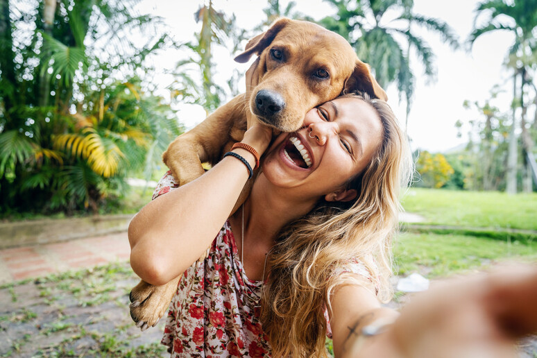 Una giovane donna sorride con il suo cane foto iStock. - RIPRODUZIONE RISERVATA