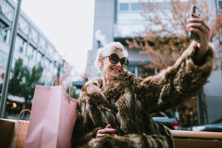 Una donna soddisfatta degli acquisti si fa un selfie, foto iStock. - RIPRODUZIONE RISERVATA