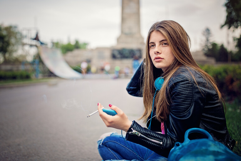 Una adolescente sola fuma una sigaretta foto iStock. - RIPRODUZIONE RISERVATA