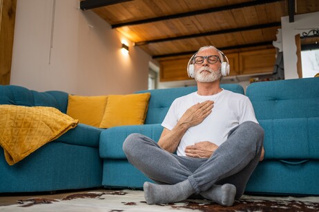 Un senior pratica la meditazione in casa foto iStock.